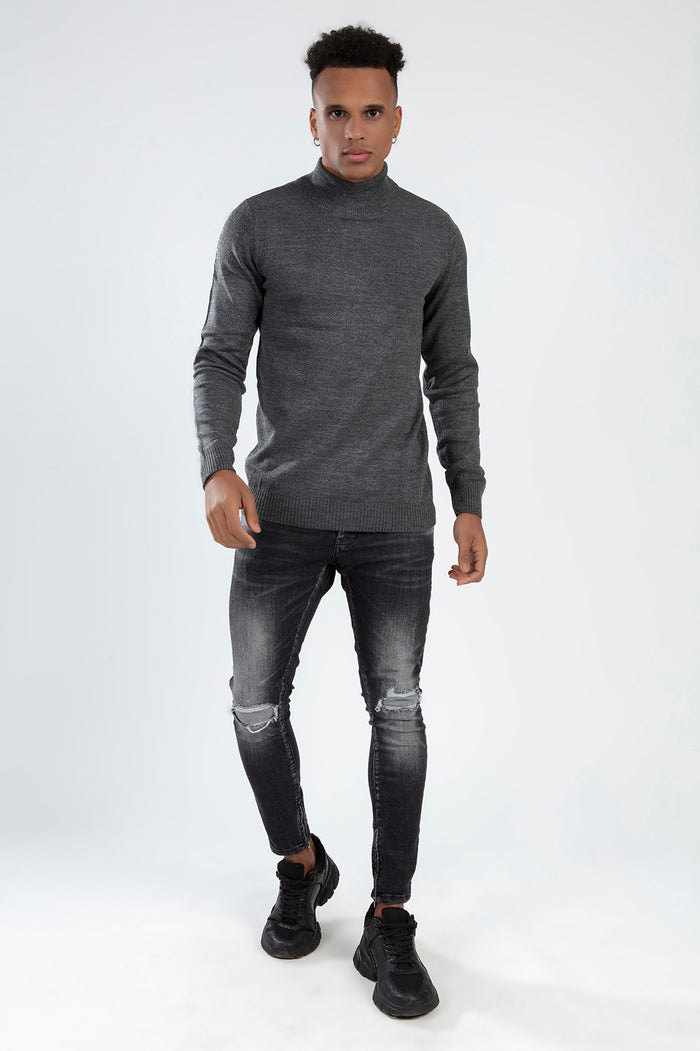 Man in the Tyson grey turtleneck knit sweater paired with black distressed skinny jeans and sneakers.