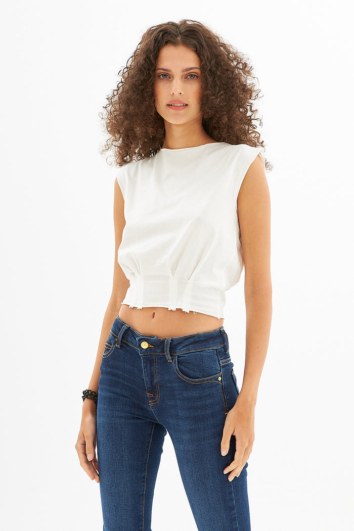 Model wearing the white Verona Essential cropped tee with pleated waist detail paired with slim-fit blue jeans.