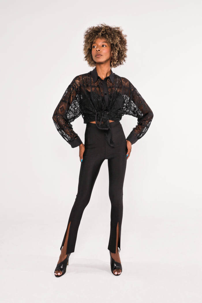Model in Zoie black lace sheer long sleeve top tied at the waist with high-waisted split hem leggings.