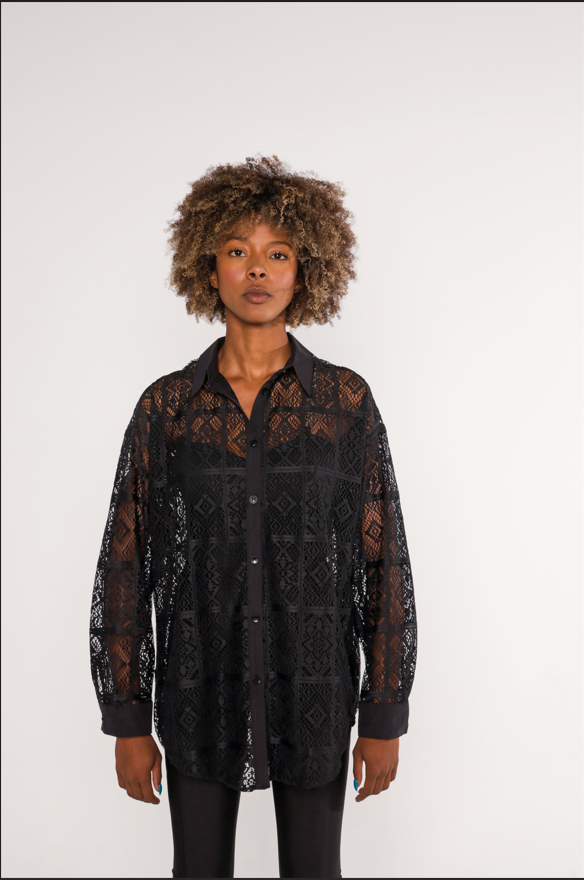 Model wearing the Zoie Top, a black sheer lace button-down shirt with long sleeves and geometric embroidery.